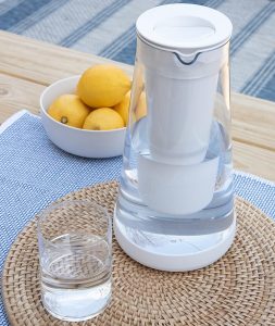 A LifeStraw Home Water Filter Pitcher is placed on the table along with a glass and a bowl of lemon