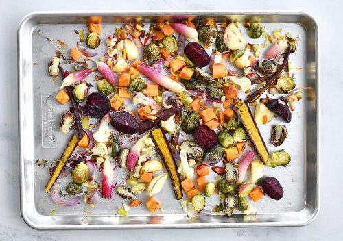 A mix of veggies are prepared in the baking sheet for baking