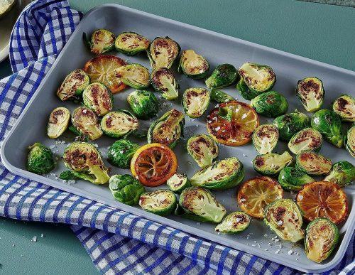 A variety of baked veggie are on the ceramic baking sheet.