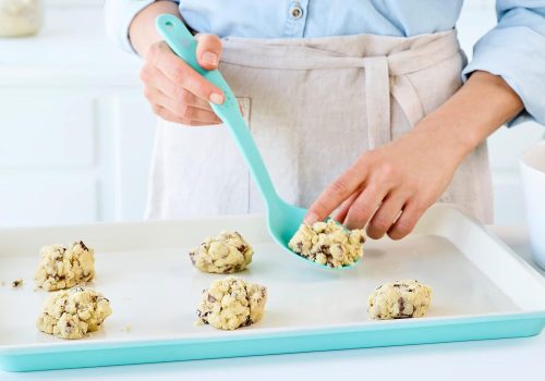 A chef is placing cookie on the baking sheet to prepare for baking. 